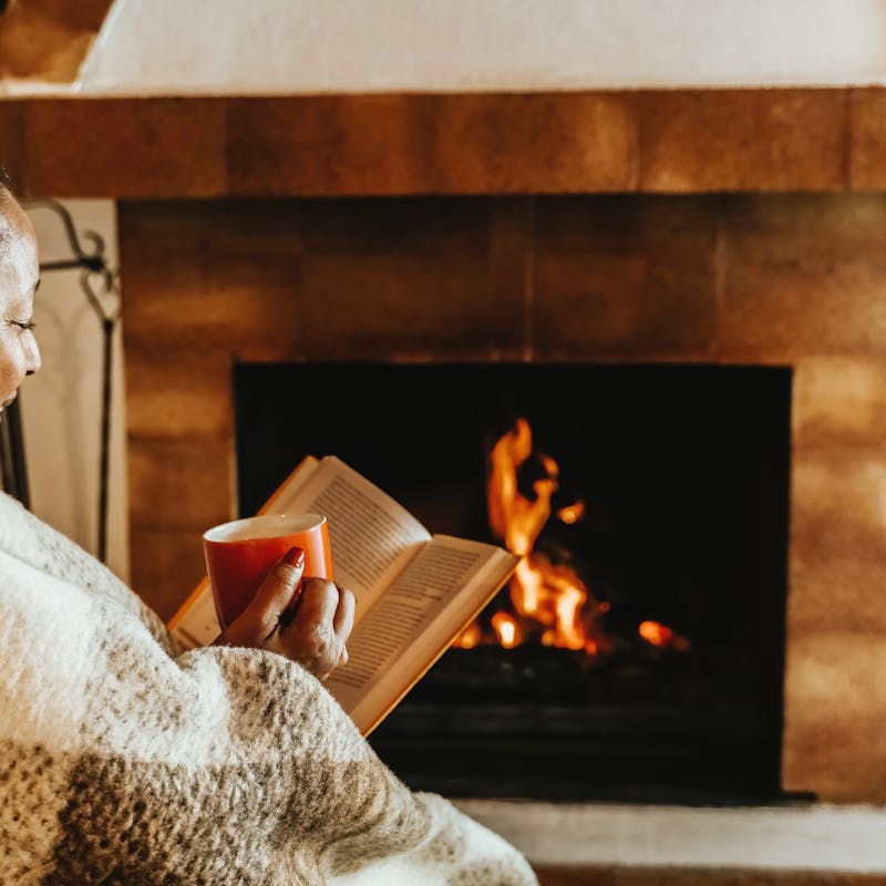 a retired woman reading and relaxing in front of the fire.